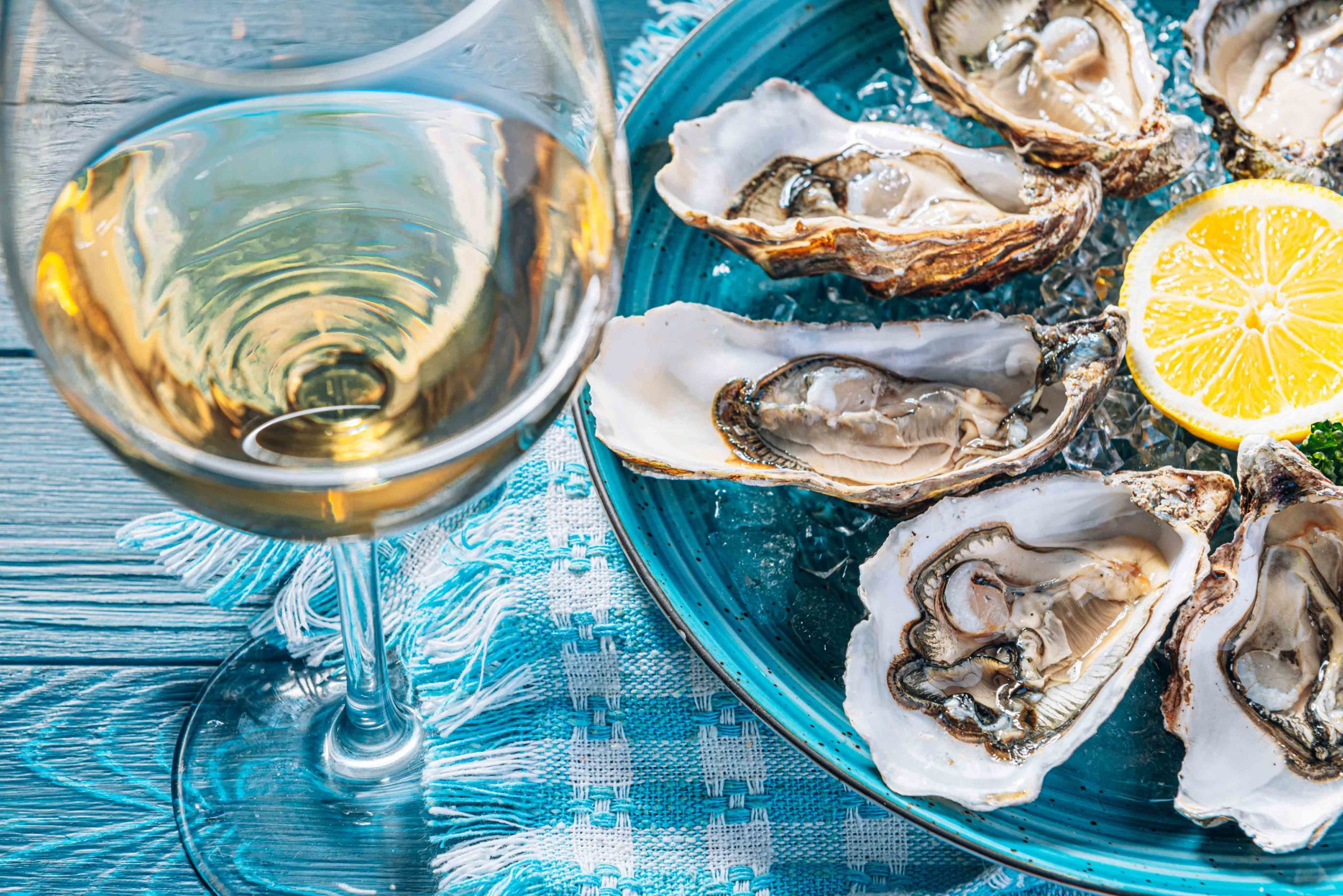 A plate of fresh oysters served with a lemon wedge, paired with a glass of white wine at Kebbells in Broadstairs.